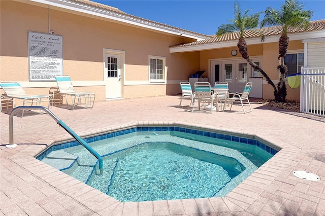 view of swimming pool featuring a community hot tub, a patio, and french doors