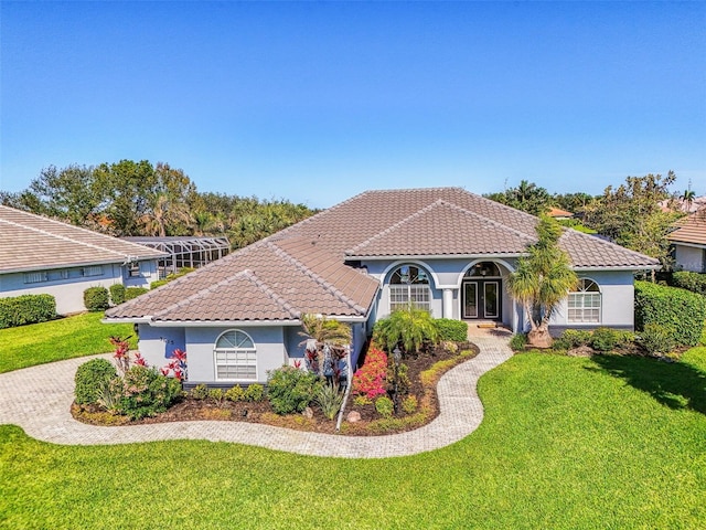 mediterranean / spanish home featuring stucco siding, a front lawn, and a tiled roof