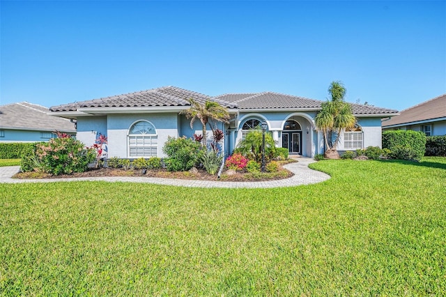 view of front of home featuring a tile roof, a front lawn, and stucco siding