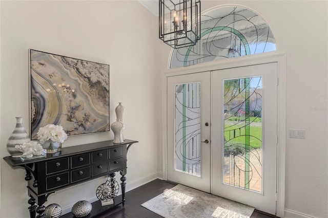 entryway featuring baseboards, dark wood-type flooring, a notable chandelier, and french doors