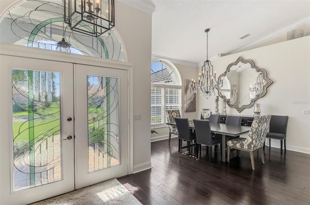 dining area featuring french doors, dark wood finished floors, ornamental molding, vaulted ceiling, and a chandelier