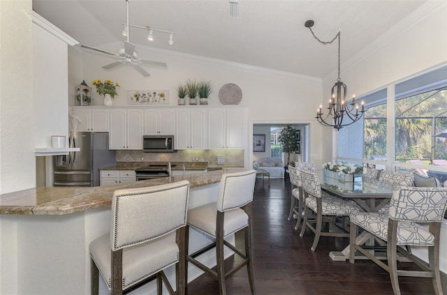 kitchen with light stone counters, stainless steel appliances, white cabinetry, tasteful backsplash, and dark wood finished floors