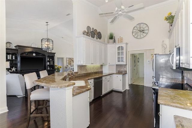 kitchen with stainless steel appliances, white cabinetry, a sink, a peninsula, and a kitchen bar