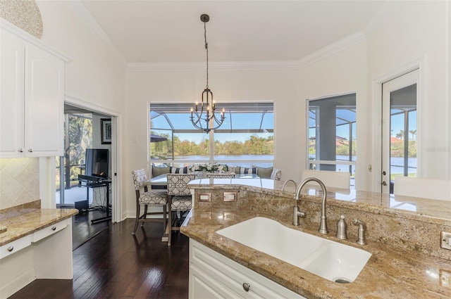 kitchen with decorative light fixtures, dark wood-type flooring, ornamental molding, a sink, and a chandelier