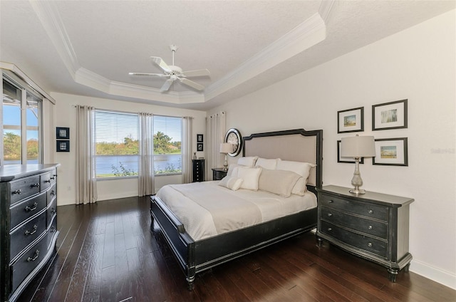 bedroom featuring baseboards, a raised ceiling, dark wood-style floors, ceiling fan, and crown molding