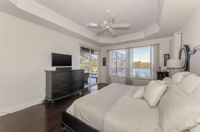 bedroom with baseboards, dark wood-style floors, access to exterior, a tray ceiling, and crown molding