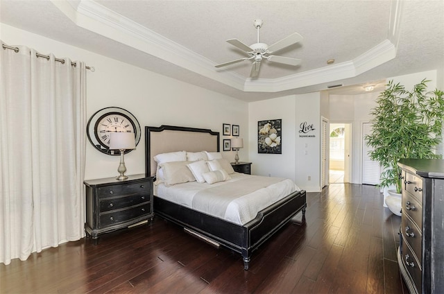 bedroom featuring a raised ceiling, ceiling fan, dark wood-style flooring, crown molding, and a textured ceiling