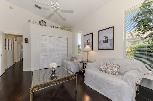 living room featuring dark wood-type flooring, visible vents, vaulted ceiling, and a ceiling fan