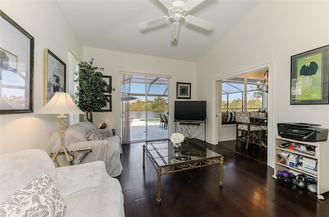 living area featuring vaulted ceiling, ceiling fan with notable chandelier, wood finished floors, and a healthy amount of sunlight