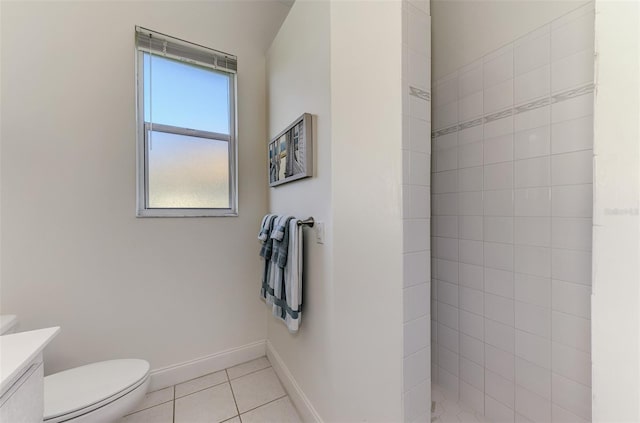 full bath featuring toilet, a tile shower, vanity, tile patterned flooring, and baseboards