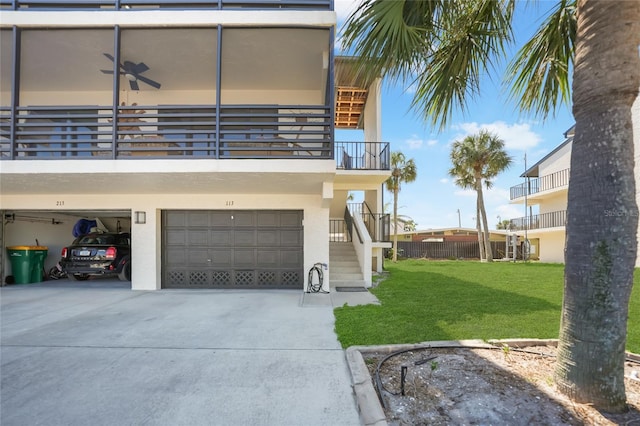 view of front facade with a front yard, stucco siding, a balcony, a garage, and driveway