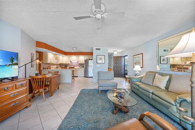 living area with light tile patterned floors, visible vents, a textured ceiling, and ceiling fan