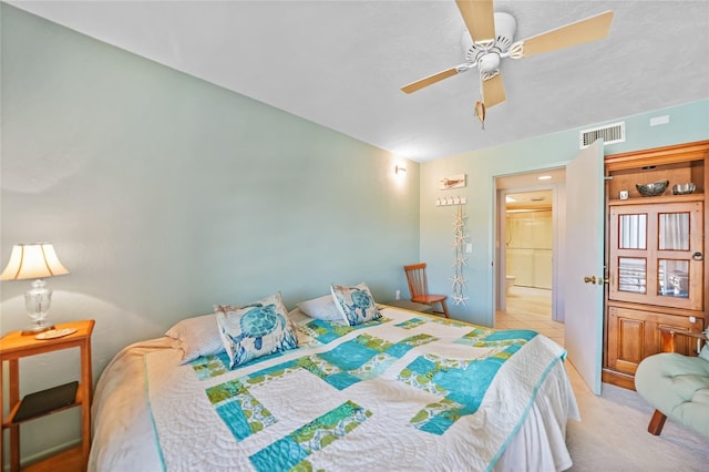 bedroom with visible vents, light carpet, ensuite bathroom, and a ceiling fan