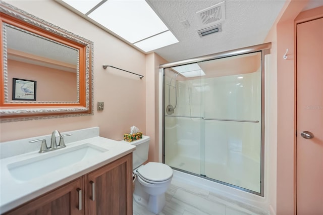 bathroom with vanity, a shower stall, toilet, and visible vents