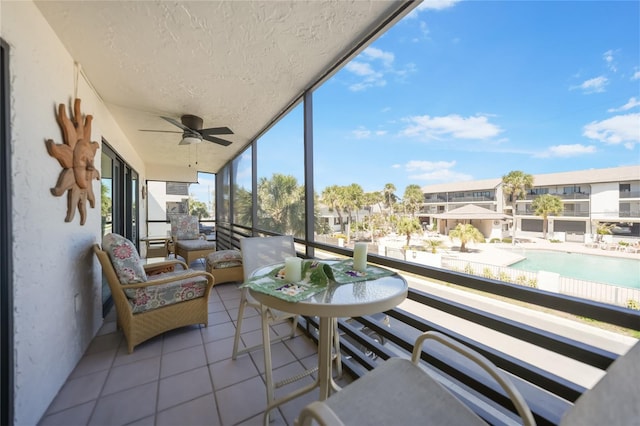 sunroom / solarium featuring a residential view and a ceiling fan