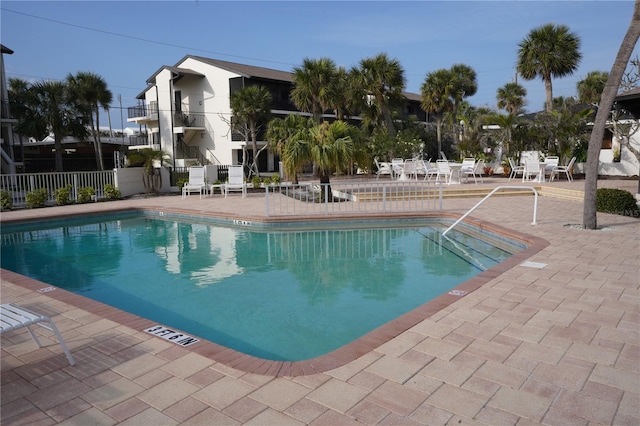 community pool with a patio area and fence