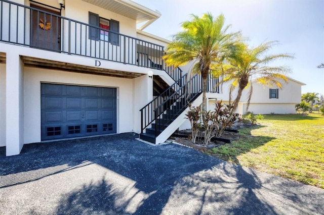 exterior space with stairway, a garage, and aphalt driveway