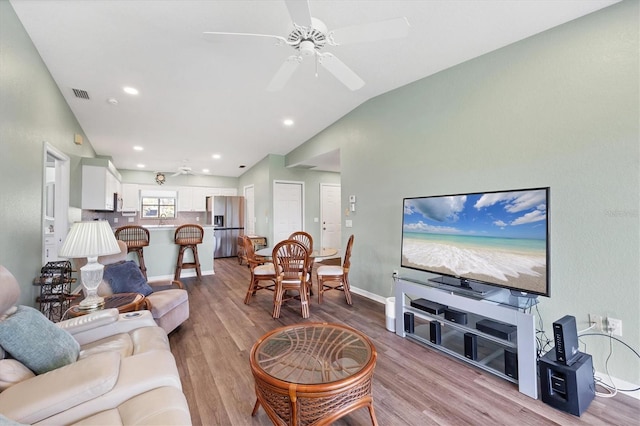 living room featuring visible vents, baseboards, ceiling fan, vaulted ceiling, and light wood-style flooring