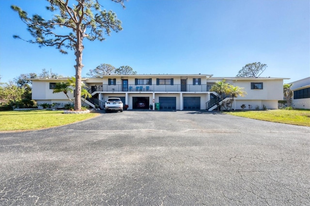 view of front of house featuring stairway, driveway, a garage, and a front yard