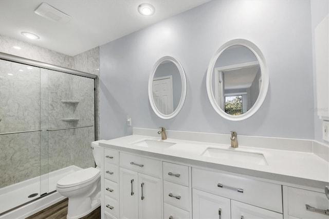 bathroom with a sink, toilet, a stall shower, and double vanity