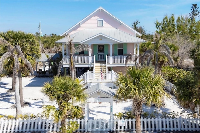 raised beach house with fence private yard, stairs, metal roof, and a porch