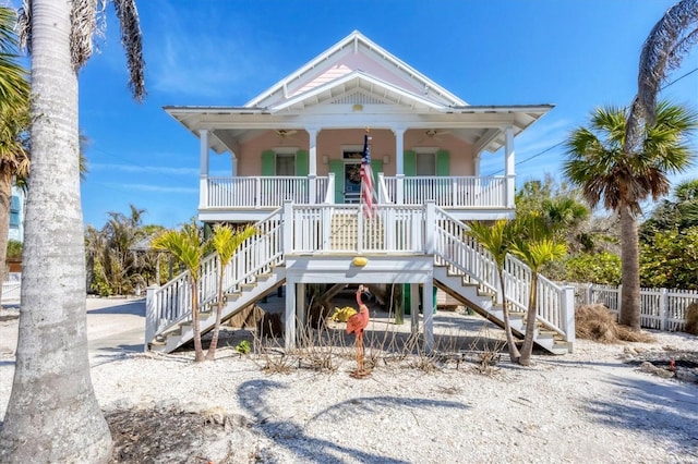 beach home with covered porch, stairs, and fence