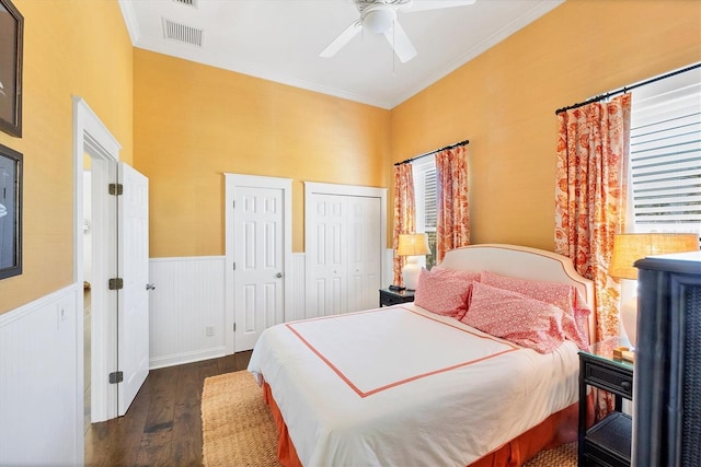 bedroom featuring a wainscoted wall, a ceiling fan, visible vents, dark wood-style floors, and crown molding