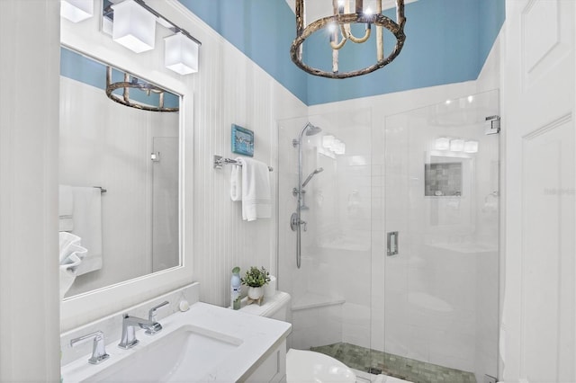 full bath with a chandelier, vanity, a shower stall, and toilet