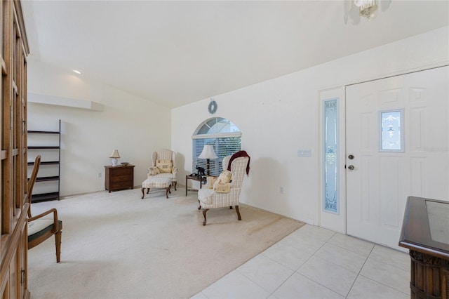 foyer featuring light carpet, light tile patterned floors, and lofted ceiling