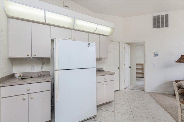 kitchen featuring light tile patterned floors, visible vents, freestanding refrigerator, light countertops, and white cabinets