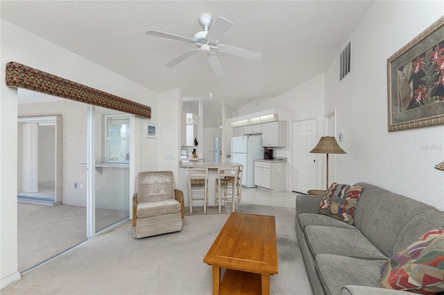 living area with visible vents, lofted ceiling, ceiling fan, a textured ceiling, and light colored carpet