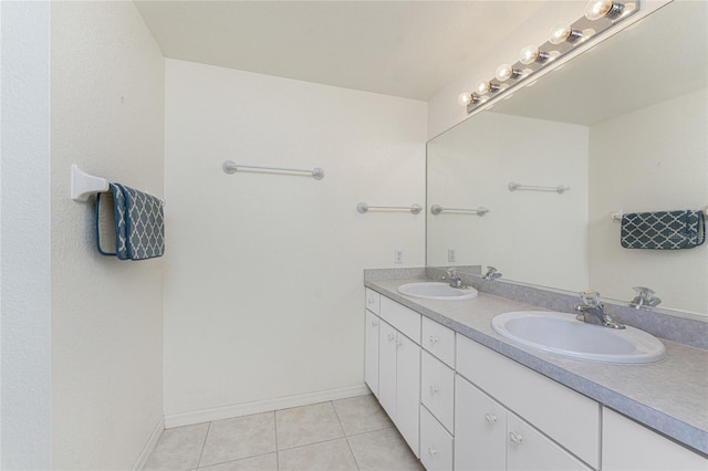 full bath with tile patterned flooring, double vanity, baseboards, and a sink