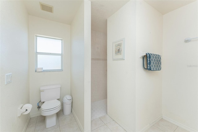 full bath with tile patterned flooring, visible vents, baseboards, toilet, and a tile shower