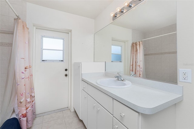 full bath featuring tile patterned floors, plenty of natural light, a tile shower, and vanity