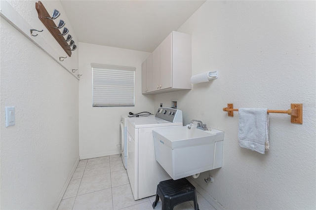 laundry room with light tile patterned floors, baseboards, washing machine and clothes dryer, cabinet space, and a sink