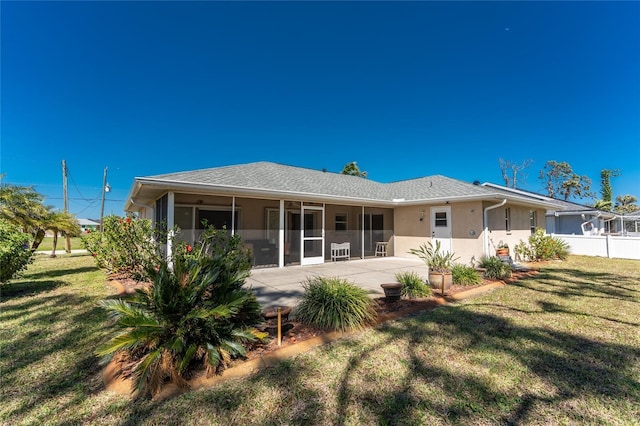 back of property with stucco siding, a patio, a yard, and a sunroom