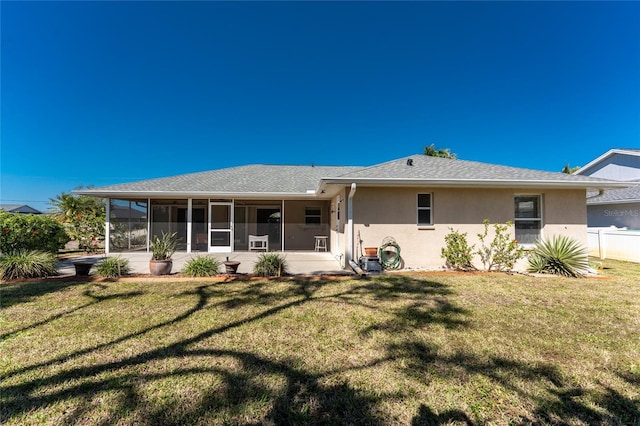 view of front of house featuring a front lawn, fence, a sunroom, and stucco siding