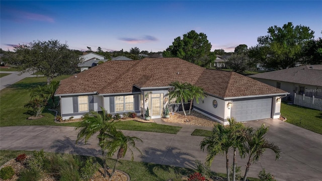 view of front of home featuring stucco siding, roof with shingles, concrete driveway, a front yard, and a garage