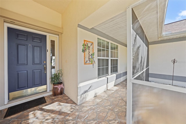 entrance to property with covered porch and stucco siding