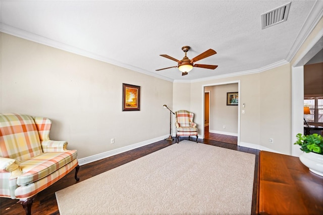 living area with a ceiling fan, dark wood-style floors, visible vents, baseboards, and crown molding