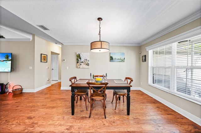 dining area featuring visible vents, light wood-style floors, and crown molding