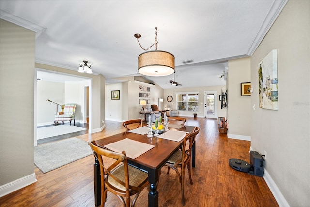 dining space featuring visible vents, baseboards, lofted ceiling, ornamental molding, and hardwood / wood-style floors