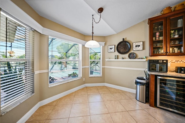 unfurnished dining area with light tile patterned floors, baseboards, beverage cooler, and a dry bar