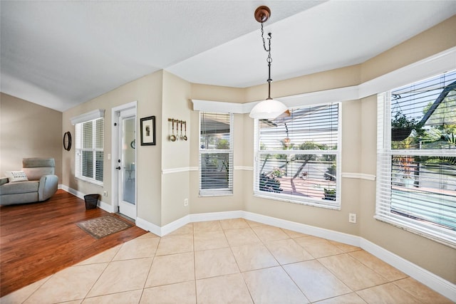 unfurnished dining area with tile patterned flooring, lofted ceiling, and baseboards