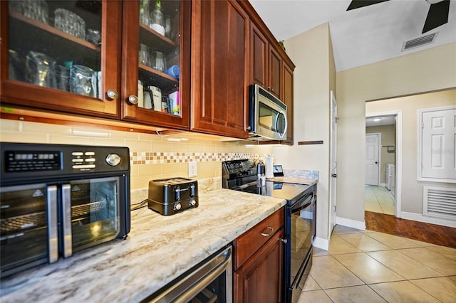 bar with stainless steel microwave, backsplash, visible vents, light tile patterned floors, and black electric range