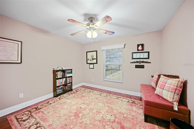 sitting room with baseboards, wood finished floors, and a ceiling fan