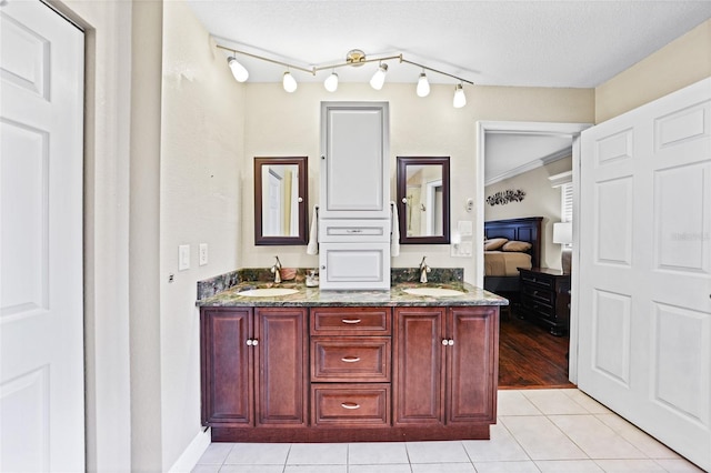 ensuite bathroom with tile patterned floors, double vanity, ensuite bathroom, and a sink