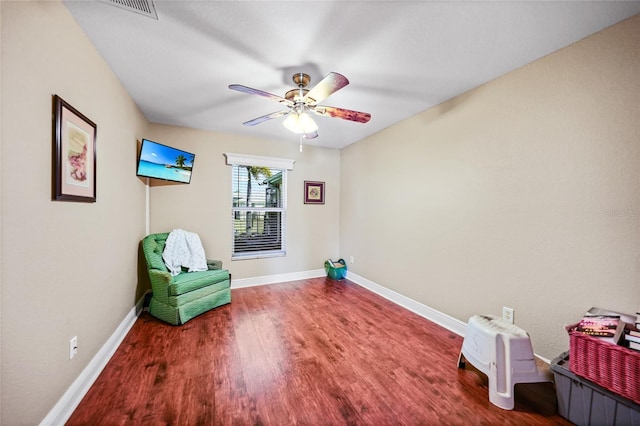 living area featuring a ceiling fan, visible vents, wood finished floors, and baseboards