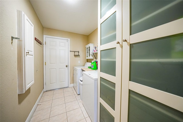 clothes washing area featuring laundry area, light tile patterned floors, separate washer and dryer, and baseboards