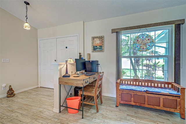 office with a textured ceiling, light wood-type flooring, and baseboards